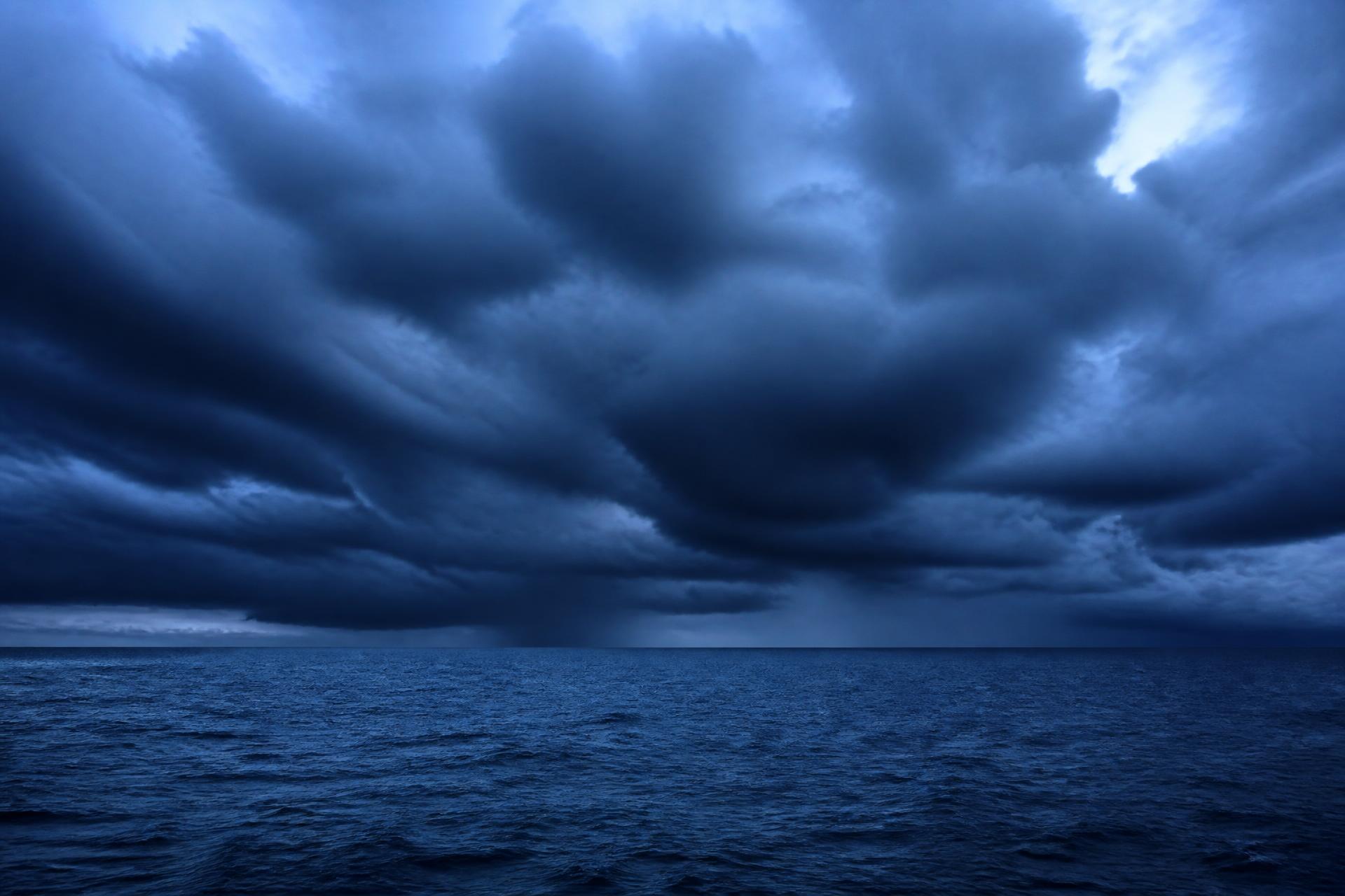 Dark storm cloud over open sea, graded cool blue